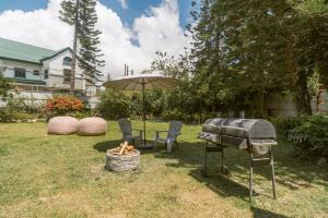 a grill and chairs and an umbrella in a yard at Baguio City Cabin House in Baguio