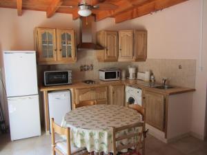 a kitchen with a table and a white refrigerator at Le Pailler d'Azor, Maison de vacances Climatisée au Calme près des Fumades in Navacelles