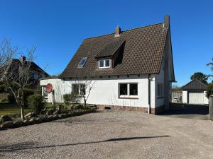 a white house with a black roof and a driveway at Ferienwohnung *Hüs Pelle* in Süddorf