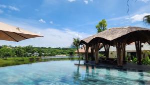 ein Resortpool mit Sonnenschirm und Wasser in der Unterkunft Hillstay Villa Resort in Ðông Sương