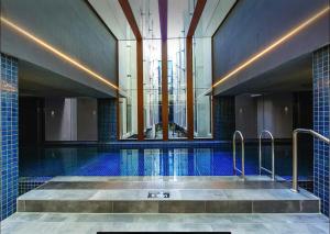 a large swimming pool with blue tiles and a building at 112 at Plush Midnight in Canberra