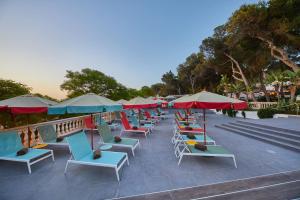 a row of lounge chairs and umbrellas on a patio at Alua Calvia in Magaluf