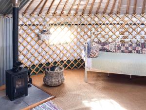 a room with a bed and a stove in a yurt at 'Villager' the Yurt at Pentref Luxury Camping in Penuwch