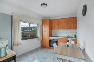 cocina con armarios de madera, mesa y ventana en El Granero, en Moya