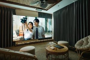 Ein TV-Bildschirm mit einem Mann und einer Frau drauf. in der Unterkunft Hillstay Villa Resort in Ðông Sương