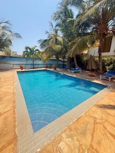 a swimming pool with blue water and palm trees at One Bed with AC, Gazebo and Pool in Diani in Ukunda Airport