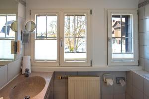 a bathroom with two sinks and two windows at Insel-Hof Reichenau Hotel-garni in Reichenau +87 photos