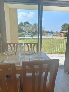 a wooden table with chairs and a table with wine glasses at Les Hauts de Balaruc - CURE THERMALE in Balaruc-les-Bains