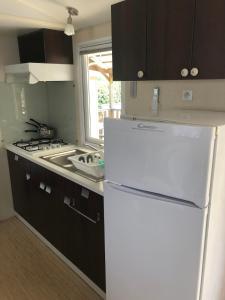 a kitchen with a white refrigerator and a sink at Domaine des Iscles mobile home clim, jardinet sans vis-à-vis in La Roque-dʼAnthéron