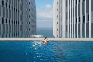 Eine Frau, die in einem Schwimmbad in einem Gebäude sitzt. in der Unterkunft Mandala Sunrise Escape in Mui Ne
