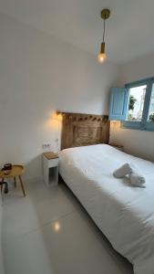 ein weißes Schlafzimmer mit einem großen Bett und einem Tisch in der Unterkunft Casa con vistas al mar y jardín in Canet de Mar