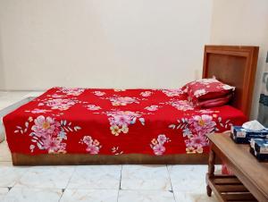 a bed with a red blanket with flowers on it at Hotel Garden View Jatrabari in Dhaka