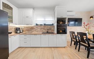una cucina con mobili bianchi e un tavolo con sedie di Villa Tria Quercus with Rooftop Pool a Vodice