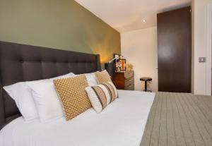 une chambre avec un grand lit blanc avec des oreillers dans l'établissement Aspire Apartments York, à York
