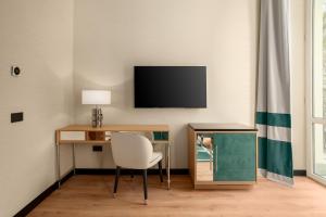 a room with a desk with a chair and a television at Room Mate Collection Mia, Rome Colosseum in Rome