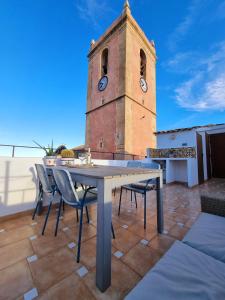a table and chairs on a roof with a clock tower at PLAZA IGLESIA HappyVila in Villajoyosa