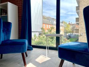 a room with two blue chairs and a window at Shoreditch Apartments by PrimeCityHosts in London