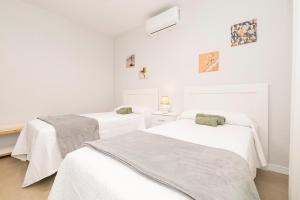 two beds in a room with white walls at Las Camelias in Chiclana de la Frontera