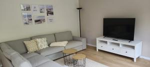a living room with a couch and a flat screen tv at Strandhygge in Flensburg