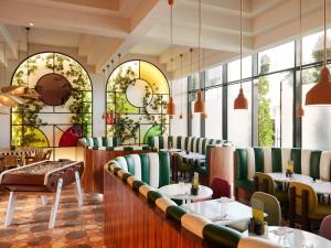 a restaurant with green chairs and tables and windows at Mama Shelter Dubai in Dubai