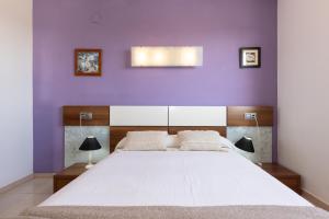 a bedroom with a white bed with a purple wall at Apartamento Mare Internum I in La Pineda