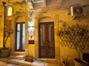 a yellow building with two doors and potted plants at alex rooms in Ragusa