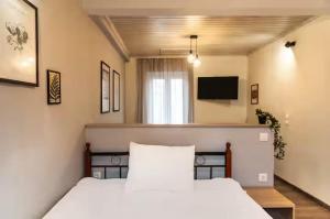 a bedroom with a white bed and a television at Burnelia Vacation Maisonette in Lefkimmi