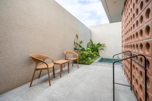 deux chaises et une table sur le balcon d'une maison dans l'établissement Vinca Villa Bali, à Kerobokan