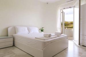 a white bedroom with a large white bed and a window at Stone Villa Nea Potidaia in Nea Potidaea