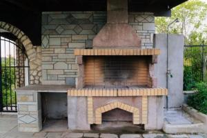 an outdoor pizza oven with a brick wall at Stone Villa Nea Potidaia in Nea Potidaea