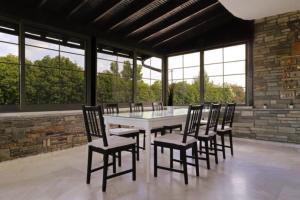 a table and chairs in a room with windows at Stone Villa Nea Potidaia in Nea Potidaea