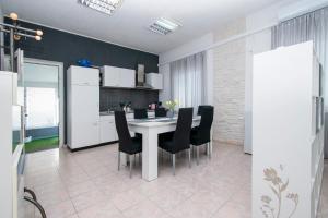 a kitchen with a white table and black chairs at Family friendly house with a swimming pool Brodarica, Sibenik - 24117 in Šibenik