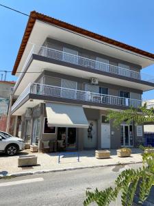 ネア・カリクラティアにあるCentral Apartmentのバルコニーと車が備わる白い大きな建物