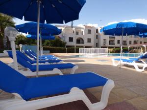 a group of blue chairs and umbrellas next to a pool at Amore Protaras Apartments in Paralimni