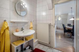 a white bathroom with a sink and a dining room at Ferienwohnungen Hof Am Deich in Hillgroven +97 photos