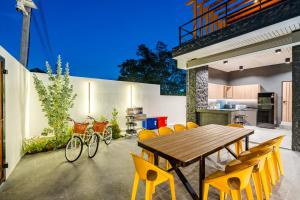 a kitchen and dining room with a wooden table and yellow chairs at Black Rocher Poolvilla Huahin in Hua Hin