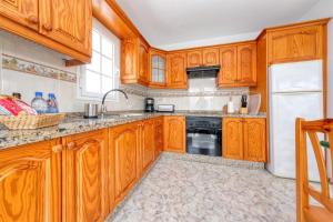 Una cocina con gabinetes de madera y un refrigerador blanco. en MarySol 5 terrace with sea views, close to the sea, en Punta Mujeres