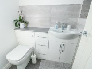 a white bathroom with a sink and a toilet at Bwlch Y Gwynt Bach in Llangefni +18 photos