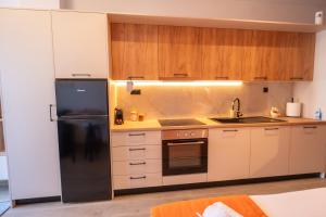 a kitchen with white cabinets and a black refrigerator at Orange Luxury apartment in agrinio in Agrinio