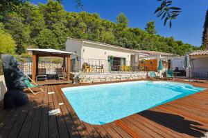 a swimming pool on a wooden deck next to a house at Auberge les Galets in Peyruis