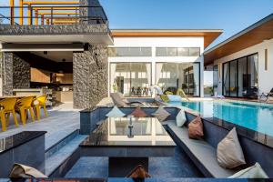 an outdoor living area with a swimming pool and a house at Black Rocher Poolvilla Huahin in Hua Hin