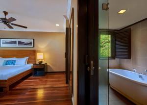 a bedroom with a bed and a bath tub next to a window at The Taaras Beach & Spa Resort in Redang Island