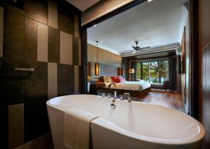 a bathroom with a bath tub and a bedroom at The Taaras Beach & Spa Resort in Redang Island