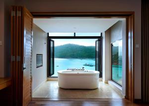 a bath tub in a room with a large window at The Taaras Beach & Spa Resort in Redang Island