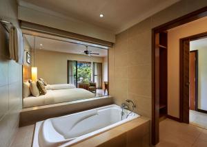 a bathroom with a tub and a bed in the mirror at The Taaras Beach & Spa Resort in Redang Island
