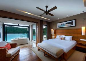 a bedroom with a bed and a tub and a couch at The Taaras Beach & Spa Resort in Redang Island