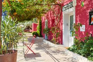 a red chair sitting outside of a pink building at Auberge les Galets in Peyruis