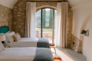 Un dormitorio con dos camas y una gran ventana. en Artu Lodge, Can Terrades, en Beuda