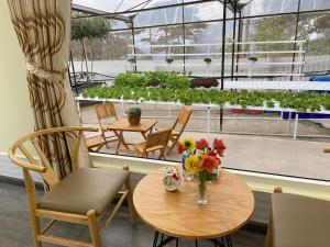Ein Tisch und Stühle mit einer Blumenvase auf einer Terrasse in der Unterkunft Vườn Nhà Đan Homestay in Da Lat