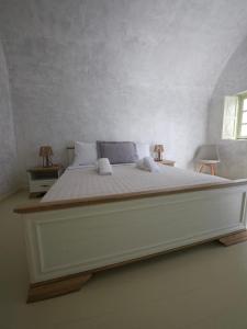 a large bed in a white room with two tables at Phaos Oia Suites in Oia +26 photos